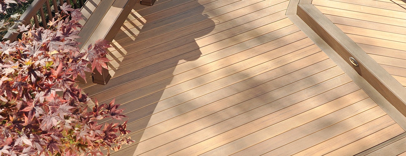 Light wood-colored composite deck surrounded by fall foliage